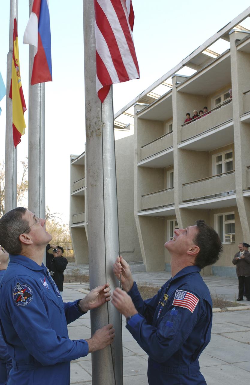 Backup Expedition 8 Commander and NASA Science Officer Bill McArthur, left, and prime Expedition 8 Commander and NASA Science Officer Michael Foale raise the American flag outside the Cosmonaut Hotel, Tuesday, Oct. 14, 2003 in a traditional ceremony as preparations continue for the Oct. 18 launch of the Soyuz TMA-3 vehicle from the Baikonur Cosmodrome to carry Foale, Expedition 8 Soyuz commander Alexander Kaleri and European Space Agency Astronaut Pedro Duque to the International Space Station. Photo Credit (NASA/Bill Ingalls)