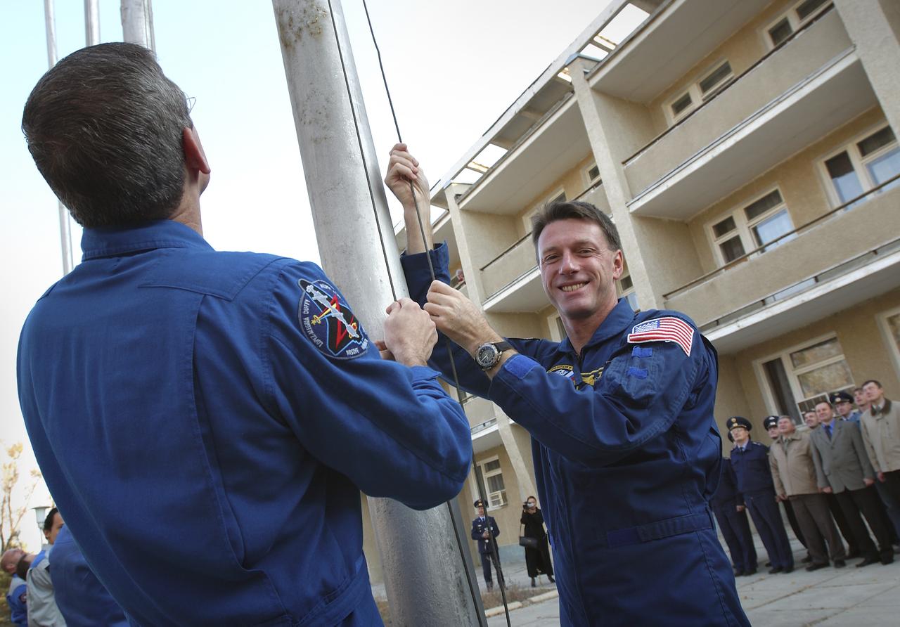 Backup Expedition 8 Commander and NASA Science Officer Bill McArthur, left, and prime Expedition 8 Commander and NASA Science Officer Michael Foale raise the American flag outside the Cosmonaut Hotel, Tuesday, Oct. 14, 2003, in a traditional ceremony in Baikonur, Kazakhstan as preparations continue for the launch Saturday, Oct. 18 of the Soyuz TMA-3 vehicle from the Baikonur Cosmodrome to carry Foale, Expedition 8 Soyuz commander Alexander Kaleri and European Space Agency astronaut Pedro Duque to the International Space Station. Photo Credit (NASA/Bill Ingalls)