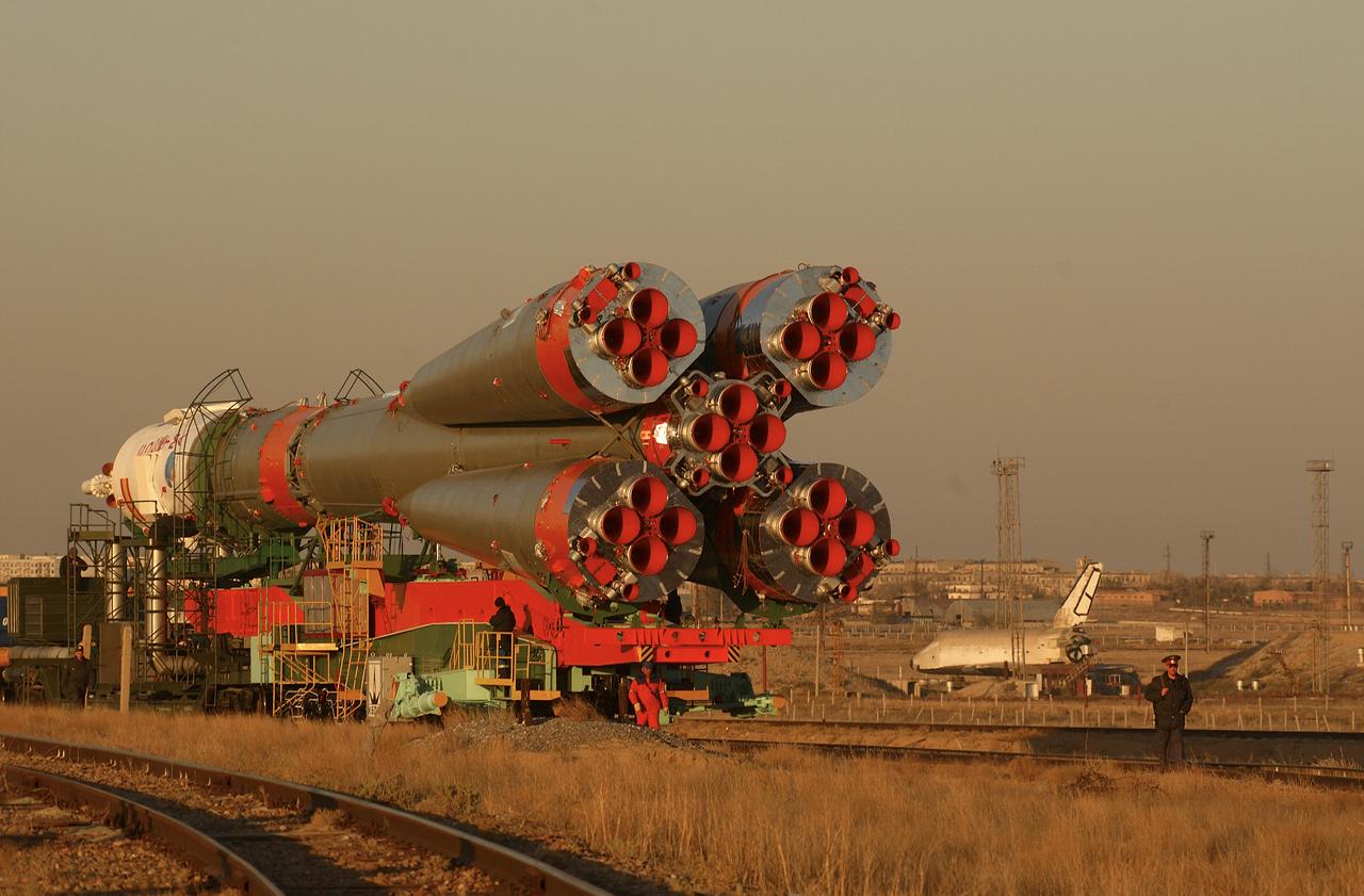With a mockup of the defunct Russian "Buran" Space Shuttle sitting nearby, right, a Soyuz TMA-3 spacecraft and its booster rocket is transported on a rail car to the launch pad at the Baikonur Cosmodrome, Kazakhstan on Thursday, Oct. 16, 2003 in preparation for liftoff Oct. 18 to carry Expedition 8 Commander and NASA Science Officer Michael Foale, Expedition 8 Soyuz Commander Alexander Kaleri and European Space Agency astronaut Pedro Duque of Spain to the International Space Station. Photo Credit (NASA/Bill Ingalls)