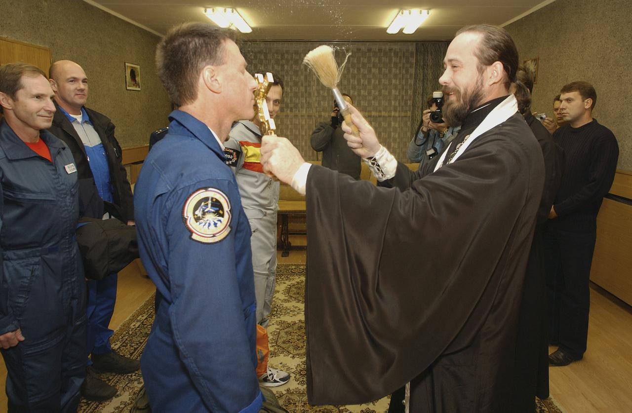 Expedition 8 Commander and NASA Science Officer Michael Foale receives the traditional prelaunch blessing from a Russian Orthodox priest in the Cosmonaut Hotel crew quarters, Saturday, Oct. 18, 2003, in Baikonur, Kazakhstan before he, Expedition 8 Commander Alexander Kaleri and European Space Agency astronaut Pedro Duque of Spain departed for the launch pad. The trio were launched a few hours later on the Soyuz TMA-3 vehicle, arriving at the International Space Station on Oct. 20. Photo Credit (NASA/Bill Ingalls)