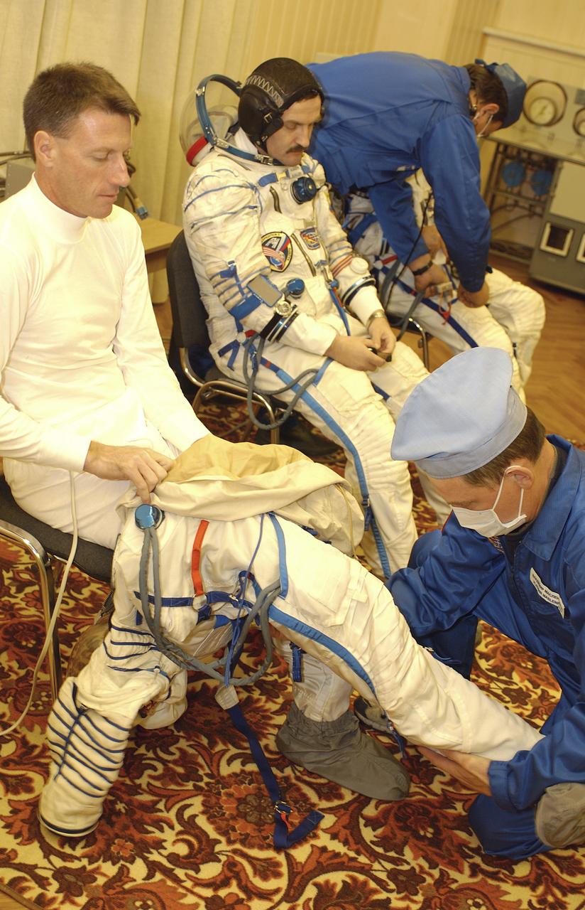 Expedition 8 Commander and NASA Scienhce Officer Michael Foale, left and Expedition 8 Soyuz Commander Alexander Kaleri suit up for launch with the assistance of technicians, Saturday, Oct. 18, 2003, prior to departure for the launch pad at the Baikonur Cosmodrome in Kazakhstan. Foale, Kaleri and European Space Agency astronaut Pedro Duque were launched on a Soyuz TMA-3 vehicle to the International Space Station, arriving on Oct. 20. Photo Credit (NASA/Bill Ingalls)