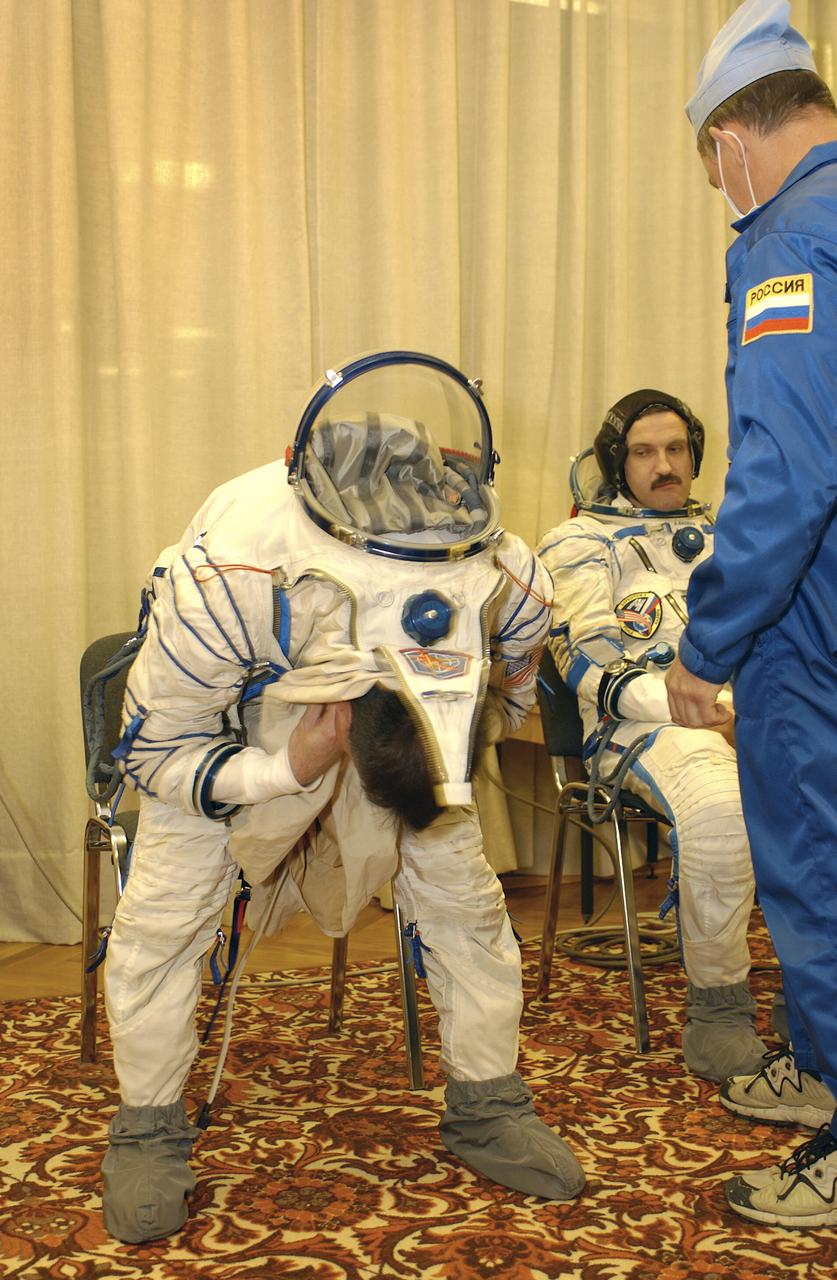 Expedition 8 Commander and NASA Scienhce Officer Michael Foale, left, works to suit up for launch as Expedition 8 Soyuz Commander Alexander Kaleri looks on, Saturday, Oct. 18, 2003, prior to departure for the launch pad at the Baikonur Cosmodrome in Kazakhstan. Foale, Kaleri and European Space Agency astronaut Pedro Duque were launched on a Soyuz TMA-3 vehicle to the International Space Station, arriving on Oct. 20. Photo Credit (NASA/Bill Ingalls)