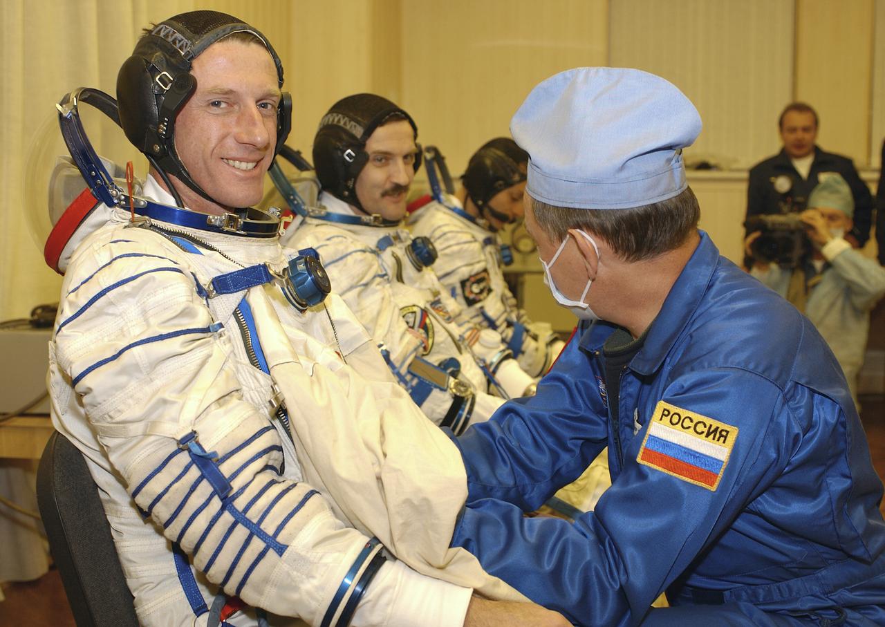 Expedition 8 Commander and NASA Scienhce Officer Michael Foale, left, smiles as Expedition 8 Soyuz Commander Alexander Kaleri makes a comment to a technician while suiting up, Saturday, Oct. 18, 2003, at the Baikonur Cosmodrome in Kazakhstan prior to their departure for the launch pad with European Space Agency astronaut Pedro Duque. The trio were launched on a Soyuz TMA-3 vehicle to the International Space Station, arriving on Oct. 20. Photo Credit (NASA/Bill Ingalls)