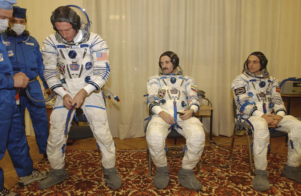 Expedition 8 Commander and NASA Science Officer Michael Foale, left, Expedition 8 Soyuz Commander Alexander Kaleri and European Space Agency astronaut Pedro Duque, right, complete suiting up, Saturday, Oct. 18, 2003, prior to departure for the launch pad at the Baikonur Cosmodrome in Kazakhstan. Foale, Kaleri and Duque were launched on a Soyuz TMA-3 vehicle to the International Space Station, arriving on Oct. 20. Photo Credit (NASA/Bill Ingalls)