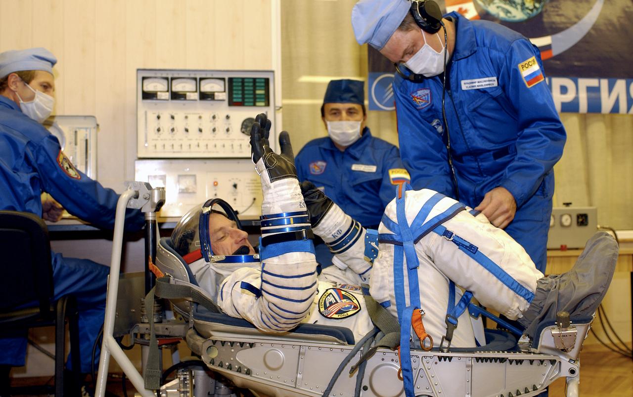 Expedition 8 Commander and NASA Science Officer Mike Foale waves to his family as technicians work on his suit, Saturday, Oct. 18, 2003, at the Baikonur Cosmodrome in Kazakhstan. Foale, Expedition 8 Soyuz Commander Alexander Kaleri and European Space Agency astronaut Pedro Duque of Spain were launched on a Soyuz TMA-3 vehicle to the International Space Station, arriving on Oct. 20. Photo Credit (NASA/Bill Ingalls)