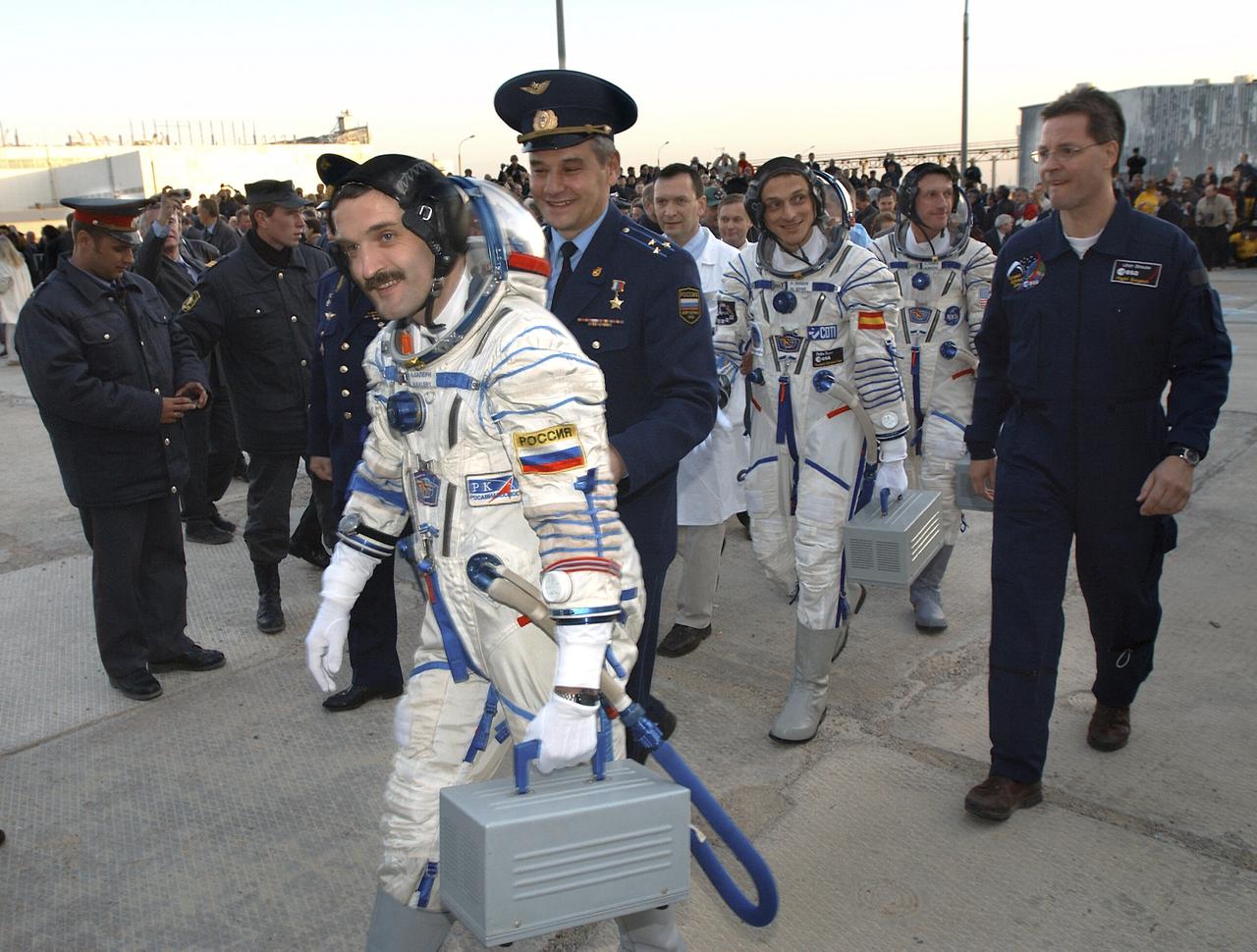 Expedition 8 Soyuz Commander Alexander Kaleri, left foreground, European Space Agency astronaut Pedro Duque of Spain and Expedition 8 Commander and NASA Science Officer Michael Foale walk to a bus at the Baikonur Cosmodrome in Kazakhstan, Saturday, Oct. 18, 2003, for transportation to the launch pad to liftoff in a Soyuz TMA-3 vehicle to the International Space Station. The trio arrived at the ISS Oct. 20. Photo Credit (NASA/Bill Ingalls)