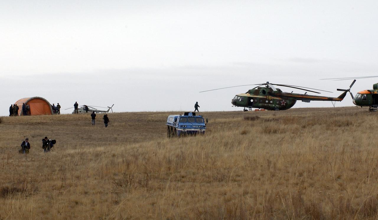 Russian Search and Rescue helicopters and an all-terrain vehicle deliver astronaut Edward T. Lu, Expedition 7 NASA International Space Station Science Officer and Flight Engineer, to his helicopter at the Soyuz TMA-2 landing site in Kazakhstan.  The Soyuz spacecraft carrying Lu; cosmonaut Yuri I. Malenchenko, Expedition 7 Mission Commander; and European Space Agency (ESA) astronaut Pedro Duque of Spain landed in Kazakhstan on Monday, October 27, 2003 at 9:41 p.m. (EST). Photo Credit: (NASA/Bill Ingalls)