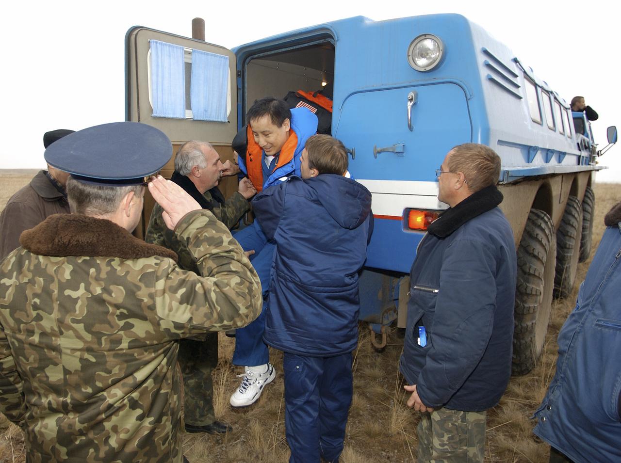 Astronaut Edward T. Lu, Expedition 7 NASA International Space Station Science Officer and Flight Engineer, is helped from a Russian all-terrain vehicle after being transported from the Soyuz TMA-2 landing site to his helicopter in Kazakhstan. The helicopter pilot salutes Lu as he departs the ATV. The Soyuz spacecraft carrying Lu; cosmonaut Yuri I. Malenchenko, Expedition 7 Mission Commander; and European Space Agency (ESA) astronaut Pedro Duque of Spain landed in Kazakhstan on Monday, October 27, 2003 at 9:41 p.m. (EST). Photo Credit: (NASA/Bill Ingalls)