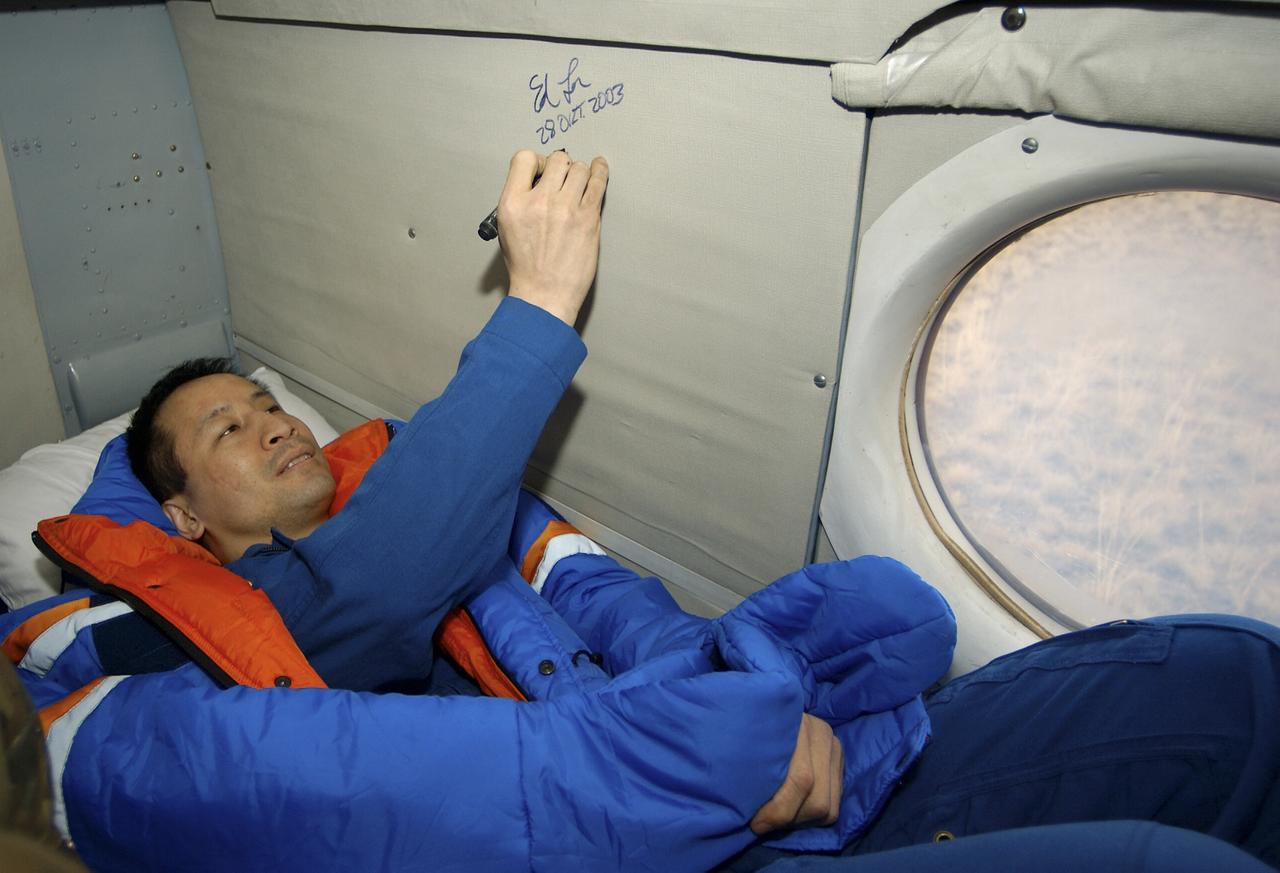 Astronaut Edward T. Lu, Expedition 7 NASA International Space Station Science Officer and Flight Engineer, signs his name on the wall of a Russian helicopter after landing in the Soyuz TMA-2 spacecraft in Kazakhstan. The Soyuz spacecraft carrying Lu; cosmonaut Yuri I. Malenchenko, Expedition 7 Mission Commander; and European Space Agency (ESA) astronaut Pedro Duque of Spain landed in Kazakhstan on Monday, October 27, 2003 at 9:41 p.m. (EST). Photo Credit: (NASA/Bill Ingalls)