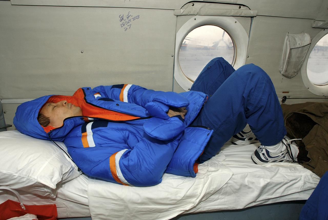 Astronaut Edward T. Lu, Expedition 7 NASA International Space Station Science Officer and Flight Engineer, sleeps onboard a Russian helicopter in Arkalyk, Kazakhstan. The helicopter had to wait out bad weather before moving on to Astana, Kazakhstan. The Soyuz TMA-2 spacecraft carrying Lu; cosmonaut Yuri I. Malenchenko, Expedition 7 Mission Commander; and European Space Agency (ESA) astronaut Pedro Duque of Spain landed in Kazakhstan on Monday, October 27, 2003 at 9:41 p.m. (EST). Photo Credit: (NASA/Bill Ingalls)