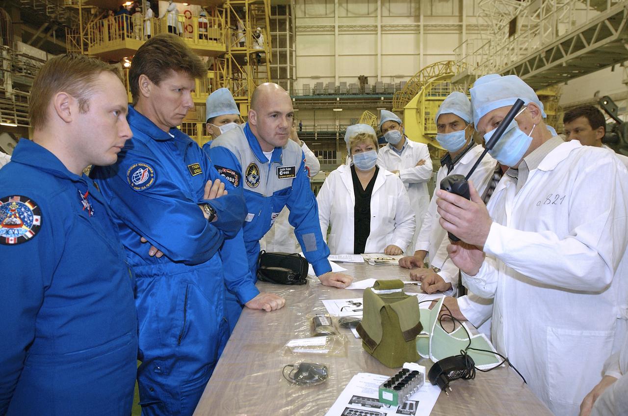 Expedition 9 Science Officer and Flight Engineer Mike Fincke, left, Expedition 9 Commander Gennady Padalka, second from left and Flight Engineer and European Space Agency astronaut Andre Kuipers of the Netherlands listen to instructions on satellite phone and GPS use at building 254 at Baikonur Cosmodrome Wednesday, April 14, 2004, in Baikonur, Kazakhstan. Photo Credit: (NASA/Bill Ingalls)