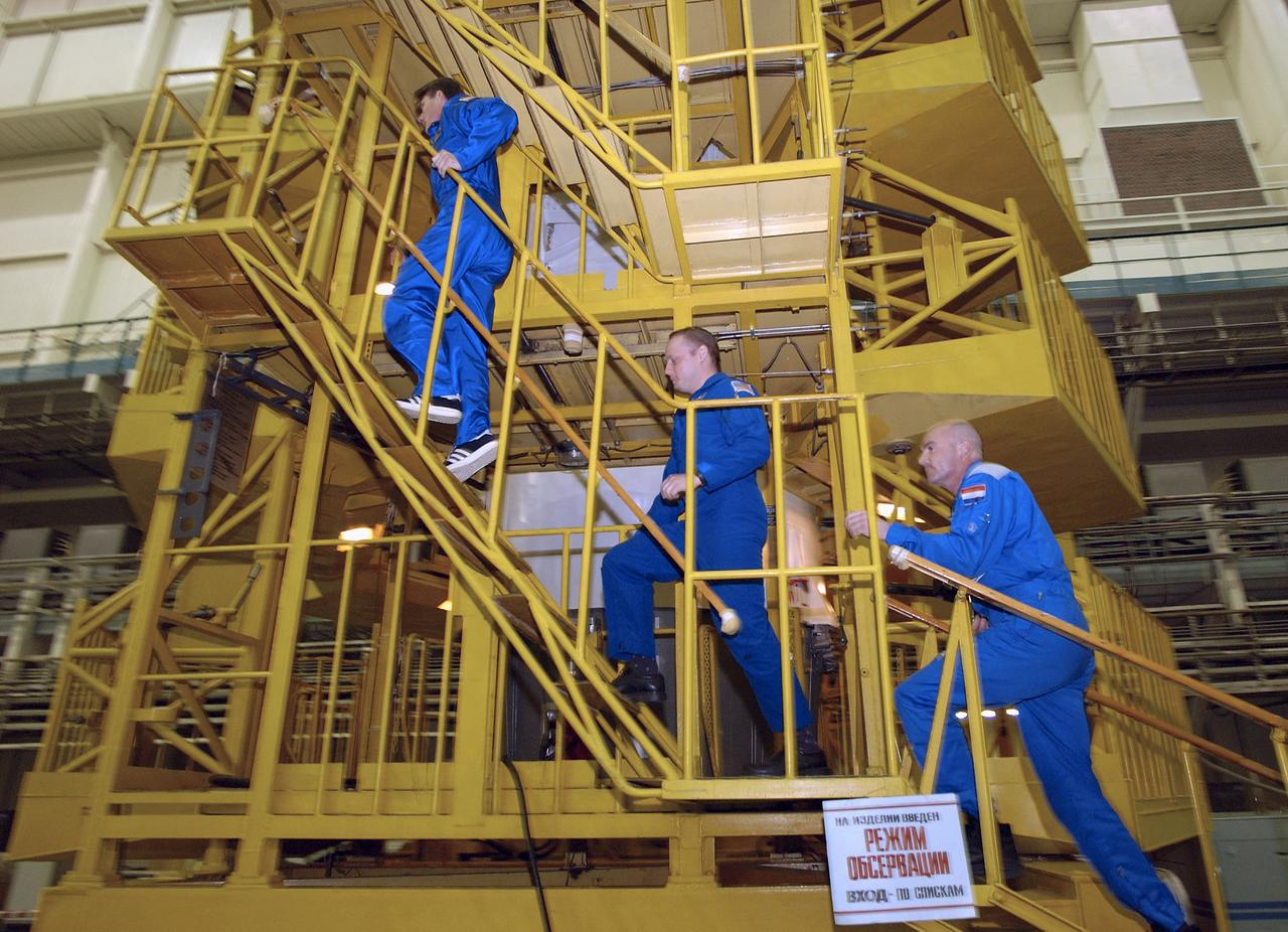 Expedition 9 Commander Gennady Padalka, left, NASA Science Officer Mike Fincke, center and Flight Engineer and European Space Agency astronaut Andre Kuipers of the Netherlands climb the workstand around the Soyuz capsule for their final fit check at building 254 at the Baikonur Cosmodrome, Wednesday, April 14, 2004, in Baikonur, Kazakhstan. Photo Credit: (NASA/Bill Ingalls)