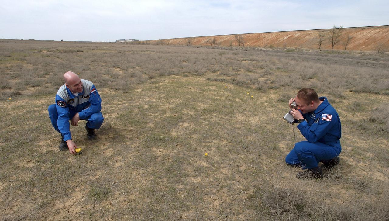 Flight Engineer and NASA Science Officer Mike Fincke, right, makes a photograph of European Space Agency astronaut Andre Kuipers of the Netherlands with a desert tulip just outside the gates to the Soyuz launch pad, Wednesday, April 14, 2004 in Baikonur, Kazakhstan.  Photo Credit: (NASA/Bill Ingalls)