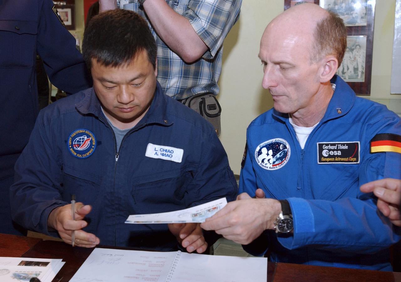 NASA Expedition 9 backup Commander Leroy Chiao, left and backup European Space Agency astronaut Gerhard Thiele of Germany sign books, envelops and mementoes in the space museum located at the Baikonur Cosmodrome, Wednesday, April, 14, 2004, in Baikonur, Kazakhstan. Photo Credit: (NASA/Bill Ingalls)