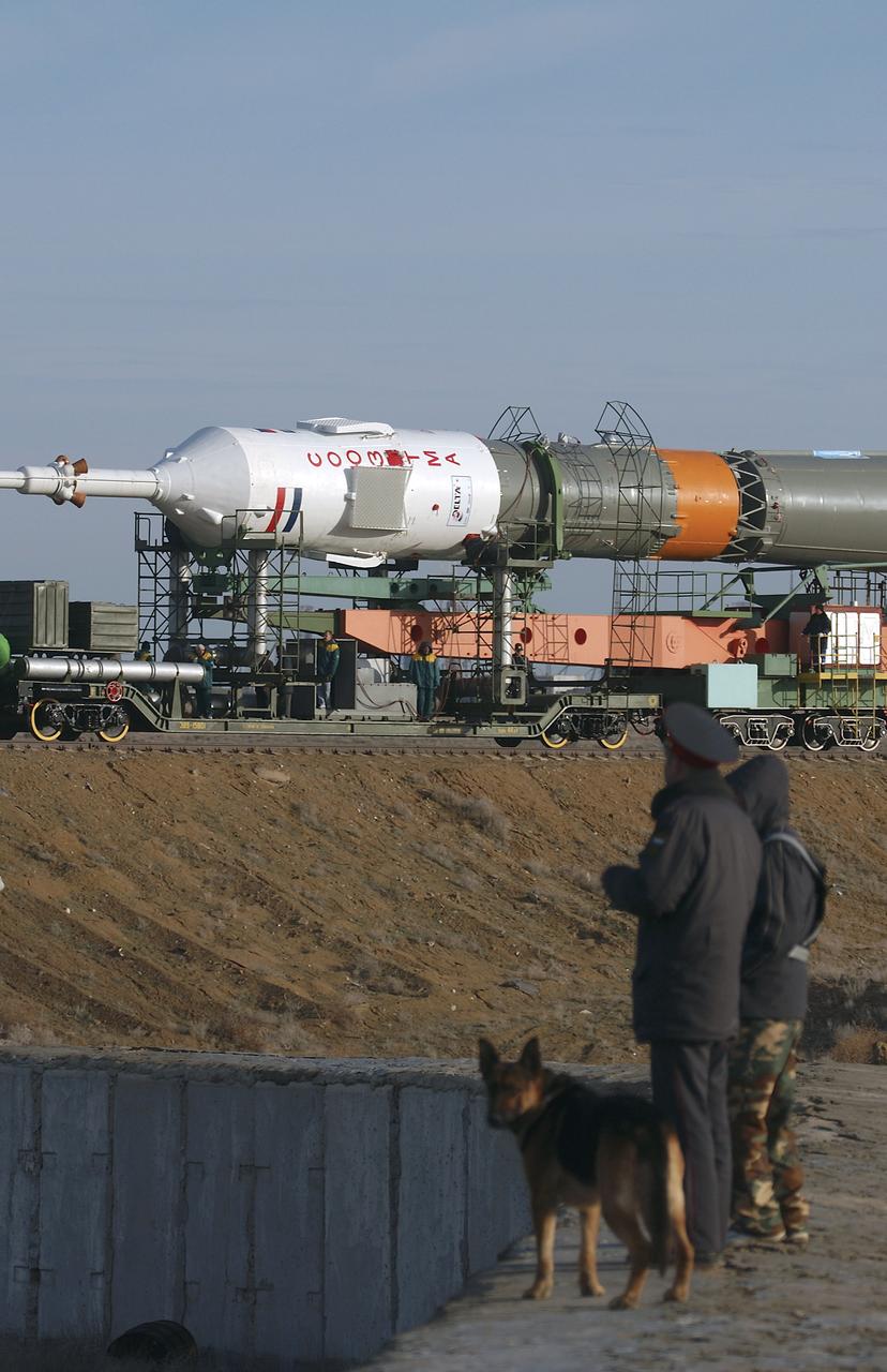 Security Officers with their dog watch as the Soyuz TMA-4 capsule and its booster rocket begin to roll to the launch pad at the Baikonur Cosmodrome on Saturday, April 17, 2004, in Baikonur, Kazakhstan in preparation for the launch of the Expedition 9 crew and a European researcher to the International Space Station on April 19. The Soyuz vehicle is transported to the launch pad horizontally on a railcar from its processing hangar in a process that takes about 2.5 hours to complete. Photo Credit: (NASA/Bill Ingalls)