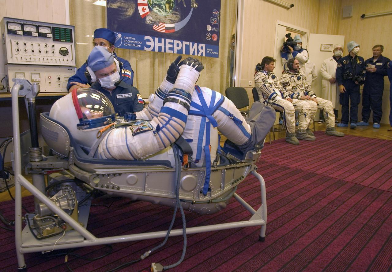 Flight Engineer and NASA Science Officer Mike Fincke gets his suit pressure checked prior to launch, while his crew mates Expedition 9 Commander Gennady Padalka, left and European Space Agency astronaut Andre Kuipers of the Netherlandsare seated in the background, Monday, April 19, 2004, in Baikonur, Kazakhstan.  Photo Credit: (NASA/Bill Ingalls)