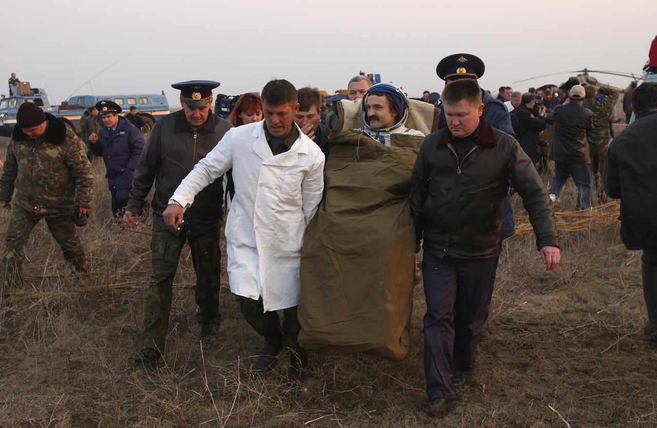 Soyuz Flight Engineer Alexander Kaleri is carried in a chair from the Soyuz landing site to an inflatable medical tent after he and Expedition 8 Commander Mike Foale and European Space Agency astronaut Andre Kuipers, of the Netherlands, landed in north central Kazakhstan, Friday, April 30, 2004, in a Soyuz TMA-3 capsule. Foale and Kaleri completed 195 days in space aboard the International Space Station, while Kuipers returned after an 11-day research mission as part of a commercial agreement between ESA and the Russian Federal Space Agency. Photo Credit: (NASA/Bill Ingalls)