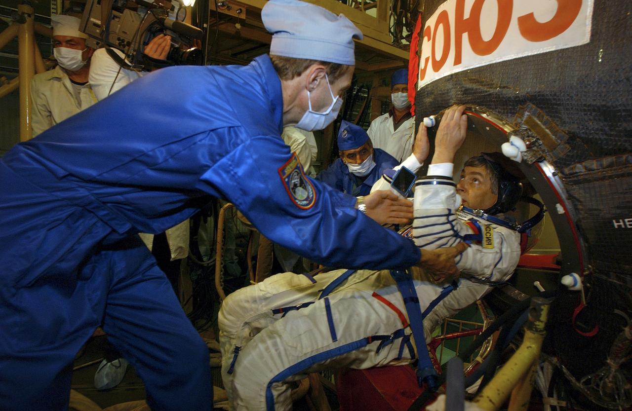 A technician assists Yuri Shargin upon exiting the Soyuz capsule after a dress rehearsal of launch day activities, Friday, Oct. 5, 2004, at the Baikonur Cosmodrome in Kazakhstan. Photo Credit: (NASA/Bill Ingalls)