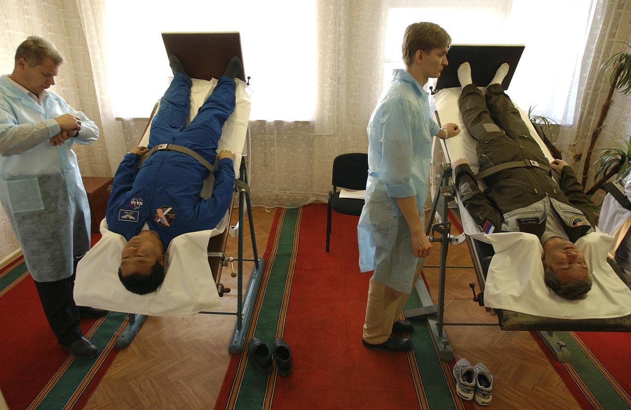 Expedition 10 Commander Leroy Chiao, left, and Russian Space Forces cosmonaut Yuri Shargin undergo physical testing on a mechanized tilt table at their crew quarters in Baikonur, Kazakhstan, Friday, October 8, 2004, in preparation for launch with Flight Engineer and Soyuz Commander Salizhan Sharipov to the International Space Station on October 14. The tilt table is used to condition the crewmembers' cardiovascular system against the effects of weightlessness once in orbit.  Photo Credit:  (NASA/Bill Ingalls)