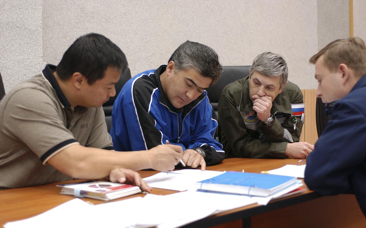 Expedition 10 Commander Leroy Chiao, left, Flight Engineer and Soyuz Commander Salizhan Sharipov and Russian Space Forces cosmonaut Yuri Shargin review their launch procedures in their flight data file with a Russian trainer, Friday, October 8, 2004, at their crew quarters in Baikonur, Kazakhstan as they prepare for liftoff to the International Space Station October 14.  Photo Credit: (NASA/Bill Ingalls)