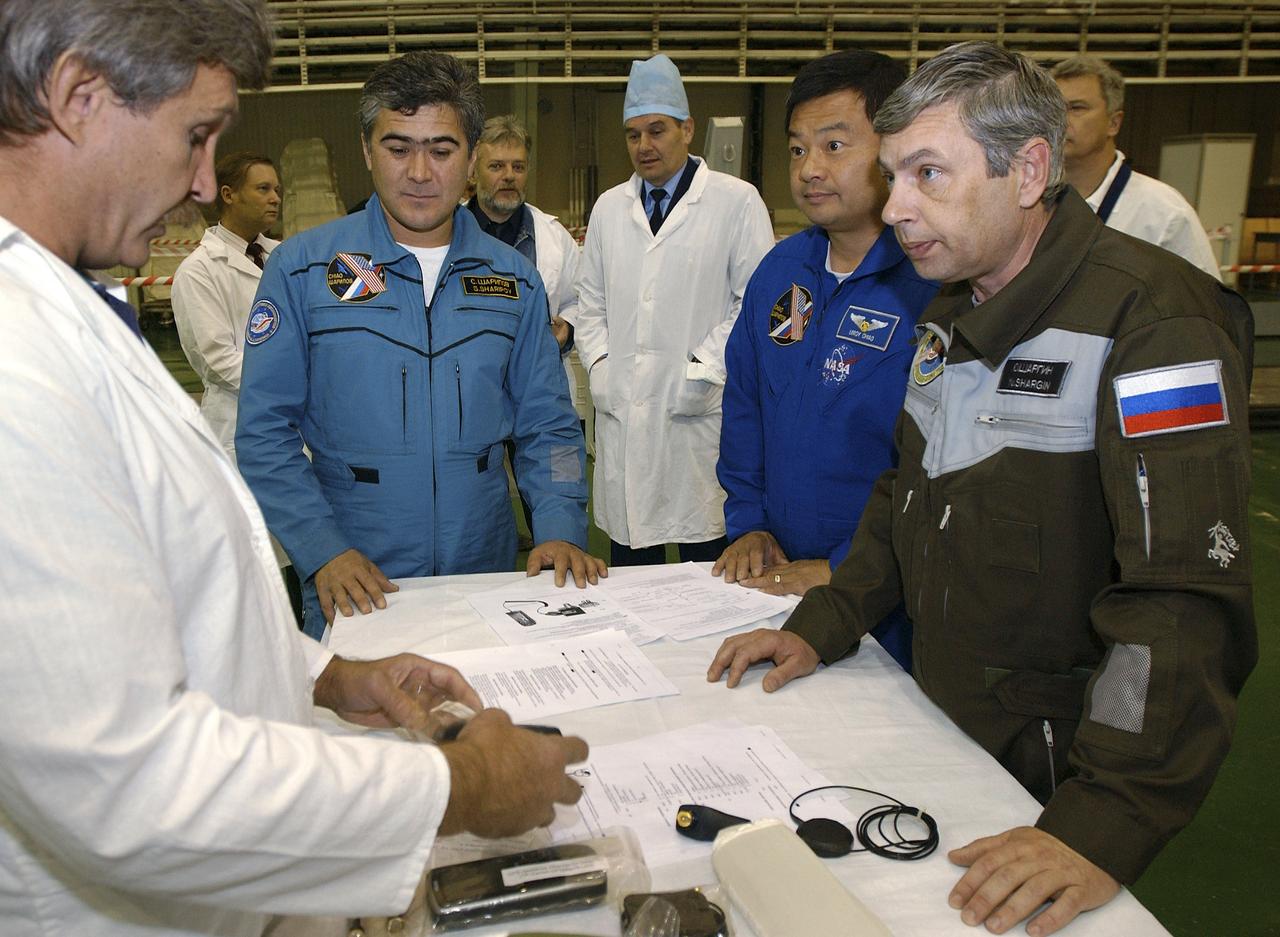 Expedition 10 Flight Engineer and Soyuz Commander Salizhan Sharipov, left, Expedition 10 Commander and NASA Science Officer Leroy Chiao and Russian Space Forces cosmonaut Yuri Shargin are given a review of the GPS and Satellite phone systems after having conducted a final inspection of their Soyuz TMA-5 spacecraft on Saturday, October 9, 2004, at the Baikonur Cosmodrome in Kazakhstan in preparation for their launch October 14 to the International Space Station.  The Soyuz vehicle will be mated to its booster rocket October 11 in preparation for its rollout to the Central Asian launch pad October 12.  Photo Credit: (NASA/Bill Ingalls) 