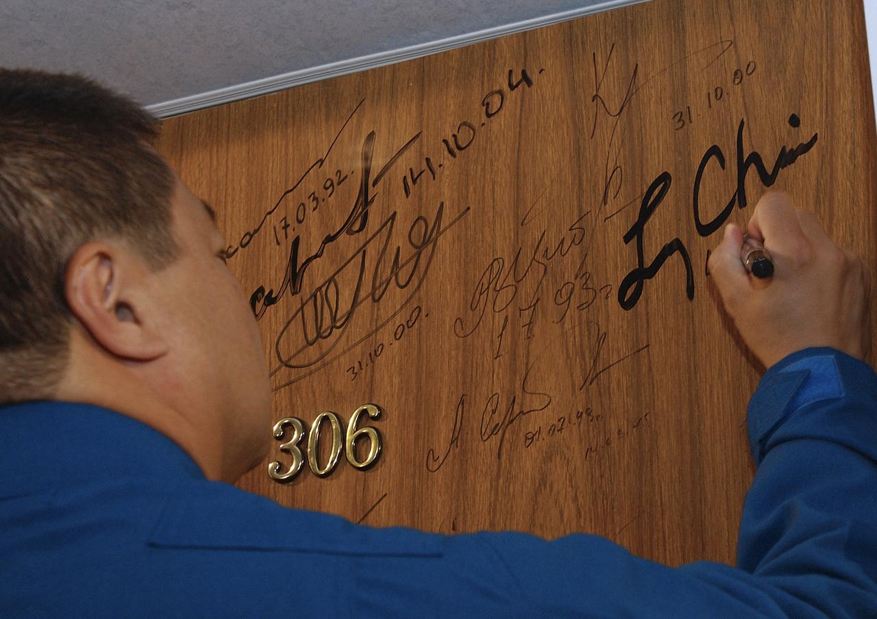 Expedition 10 Commander Leroy Chiao does the traditional door signing prior to his departure from the Cosmonaut Hotel for launch, Thursday, Oct. 14, 2004, in Baikonur, Kazakhstan.  The crew will dock to the International Space Station on October 16, and Chiao and Sharipov will replace the current station crewmembers, Gennady Padalka and Mike Fincke, who will return to Earth October 24 with Shargin.  Photo Credit: (NASA/Bill Ingalls)