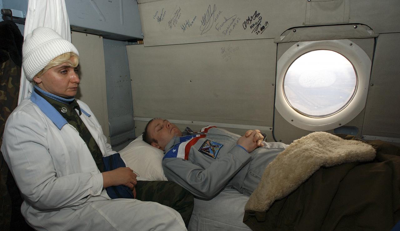A Russian nurse sits next to Expedition 9 Flight Engineer Michael Fincke, while he sleeps inside a Russian search and rescue helicopter on his way to Kustanay, Kazakhstan after landing in a Soyuz capsule 85 kilometers northeast of Arkalyk in northern Kazakhstan, Sunday, October 24, 2004.  Photo Credit: (NASA/Bill Ingalls)