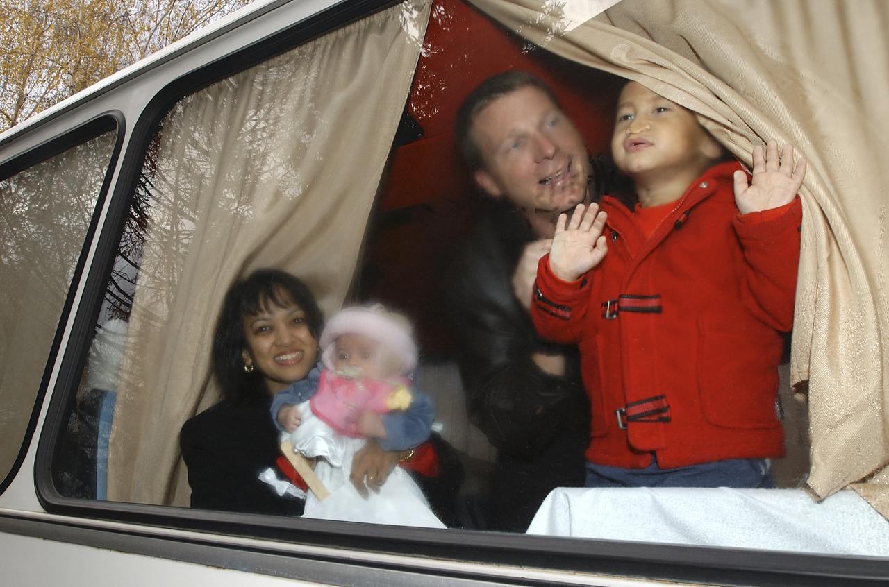 Renita Fincke, left, watches her husband, NASA astronaut Michael Fincke and Expedition 9 Flight Engineer depart from the crew bus while holding her 4 month-old baby Tarali Fincke, Sunday, October 24, 2004 in Star City, Russia. Astronaut Terry Virts helps by holding Chandra Fincke. Photo Credit: (NASA/Bill Ingalls)