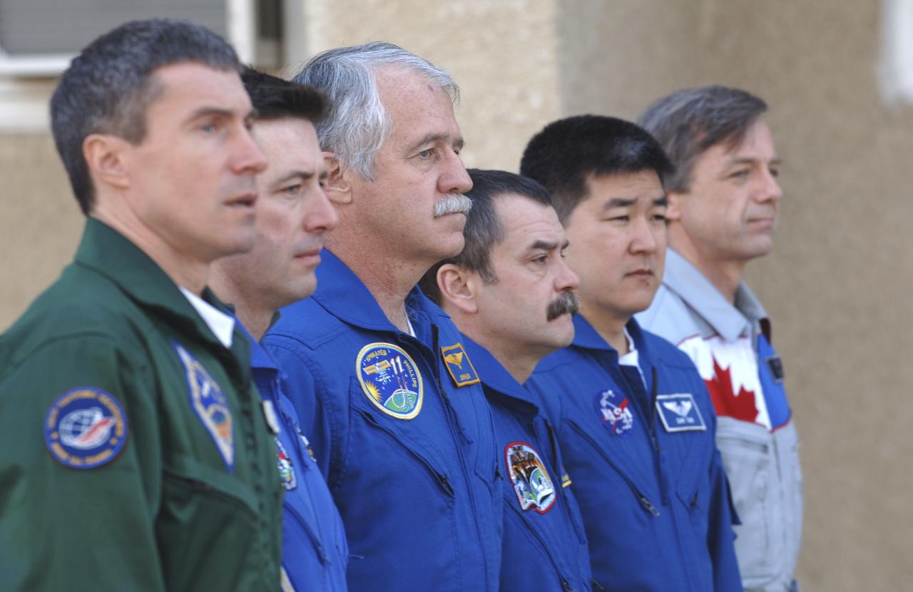 Expedition 11 Commander Sergei Krikalev, left, European Space Agency astronaut Roberto Vittori, of Italy, Flight Engineer John Phillips, third from left, along with their backups, Russian Commander Mikhail Tyurin, American Dan Tani and Robert Thirsk, of Canada, far right, participate in the traditional raising of their countries’ flags outside their crew quarters in Baikonur, Kazakhstan on Monday, April 11, 2005, during preparations for the  April 15 launch on a Soyuz TMA-6 spacecraft to the International Space Station. Krikalev and Phillips will spend six months in space and greet the first Shuttle crew to fly in more than two years when it arrives at the station, while Vittori spends eight days on the station under a commercial contract between ESA and the Russian Federal Space Agency. Photo Credit: (NASA/Bill Ingalls)