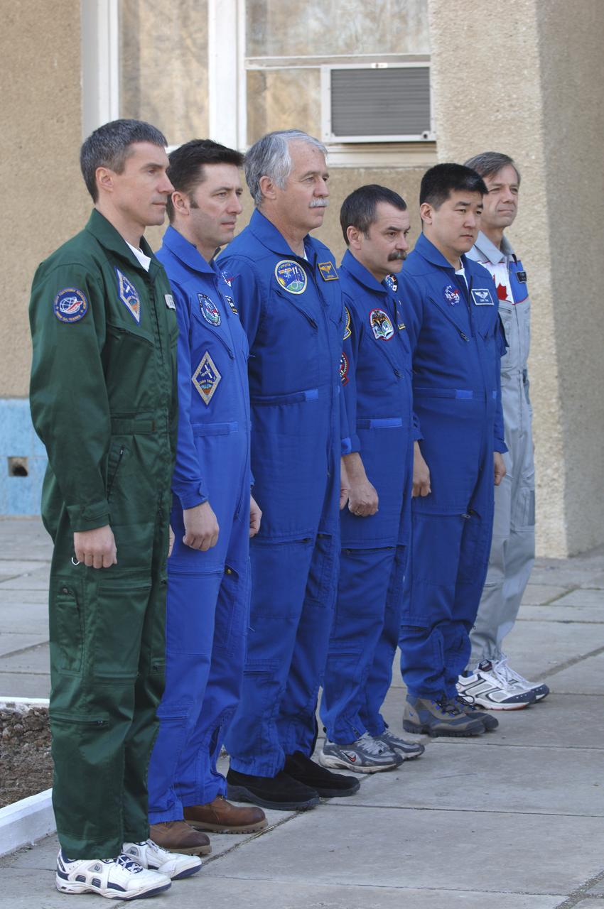 Expedition 11 Commander Sergei Krikalev, left, European Space Agency astronaut Roberto Vittori, of Italy, Flight Engineer John Phillips, third from left, along with their backups, Russian Commander Mikhail Tyurin, American Dan Tani and Robert Thirsk, of Canada, far right, participate in the traditional raising of their countries’ flags outside their crew quarters in Baikonur, Kazakhstan on Monday, April 11, 2005, during preparations for the  April 15 launch on a Soyuz TMA-6 spacecraft to the International Space Station. Krikalev and Phillips will spend six months in space and greet the first Shuttle crew to fly in more than two years when it arrives at the station, while Vittori spends eight days on the station under a commercial contract between ESA and the Russian Federal Space Agency. Photo Credit: (NASA/Bill Ingalls)