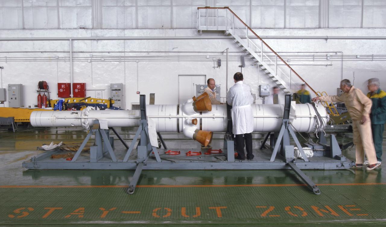 Russian technicians work, Tuesday, April 12, 2005, on mating the Soyuz TMA-6 spacecraft to the booster rocket inside the integration facility at the Baikonur Cosmodrome in Kazakhstan as preparations continued for the April 15 launch of Expedition 11 with Commander Sergei Krikalev, Flight Engineer John Phillips and European Space Agency Astronaut Roberto Vittori, of Italy, to the International Space Station. The rocket mating operation occurred on the 44th anniversary of the launch of Yuri Gagarin from the same complex to become the first human in space. Photo Credit: (NASA/Bill Ingalls)