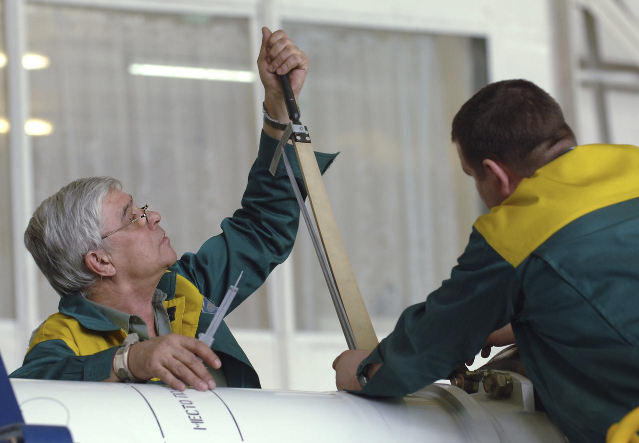 Russian technicians work, Tuesday, April 12, 2005, on mating the Soyuz TMA-6 spacecraft to the booster rocket inside the integration facility at the Baikonur Cosmodrome in Kazakhstan as preparations continued for the April 15 launch of Expedition 11 with Commander Sergei Krikalev, Flight Engineer John Phillips and European Space Agency Astronaut Roberto Vittori, of Italy, to the International Space Station. The rocket mating operation occurred on the 44th anniversary of the launch of Yuri Gagarin from the same complex to become the first human in space. Photo Credit: (NASA/Bill Ingalls)
