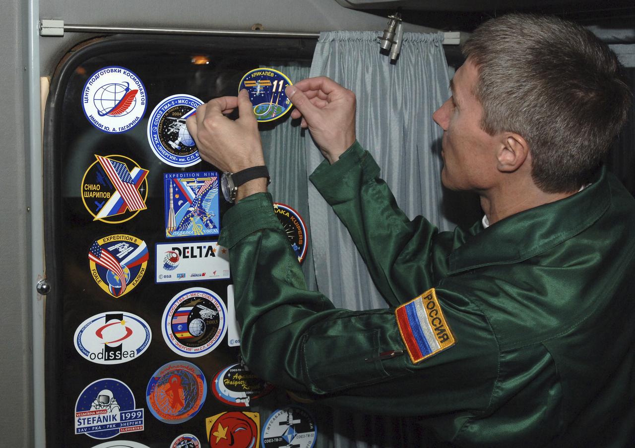 Expedition 11 crew Commander Sergei Krikalev places the Expedition 11 crew logo onboard the prime crew bus as they head to the cosmodrome for suit up, Thursday, April 14, 2005, in Baikonur, Kazakhstan. Photo Credit: (NASA/Bill Ingalls)