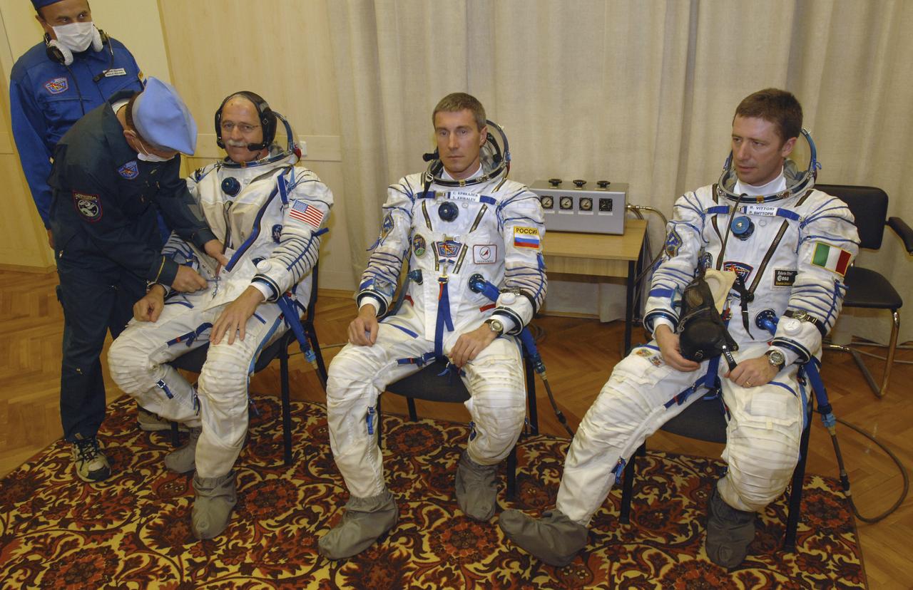 Expedition 11 Commander Sergei Krikalev, center, Flight Engineer and NASA Science Officer John Phillips, left, and European Space Agency Astronaut Roberto Vittori, of Italy, are seen as technicians work on their Russian Sokol suits prior to launch aboard the Soyuz TMA-6 spacecraft from the Baikonur Cosmodrome in Kazakhstan, Friday, April 15, 2005 for a two-day trip to the International Space Station. Photo Credit: (NASA/Bill Ingalls)