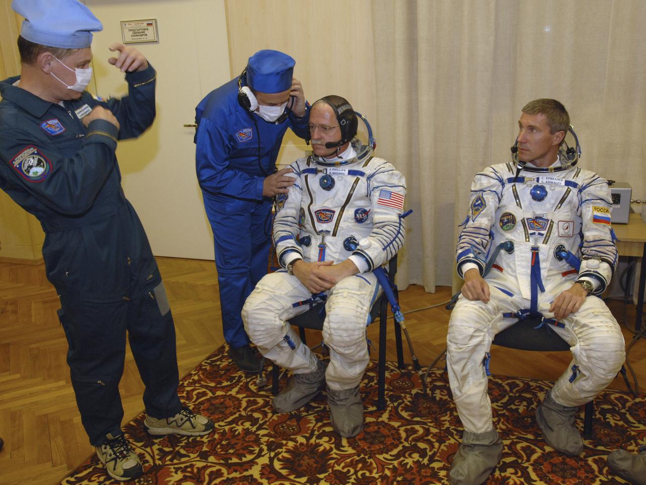 Technicians work on the Russian Sokol suits of Expedition 11 Flight Engineer and NASA Science Officer John Phillips, seated left, and Commander Sergei Krikalev, seated right, prior to launch aboard the Soyuz TMA-6 spacecraft at the Baikonur Cosmodrome in Baikonur, Kazakhstan, Friday, April 15, 2005, for a two-day trip to the International Space Station. Photo Credit: (NASA/Bill Ingalls)