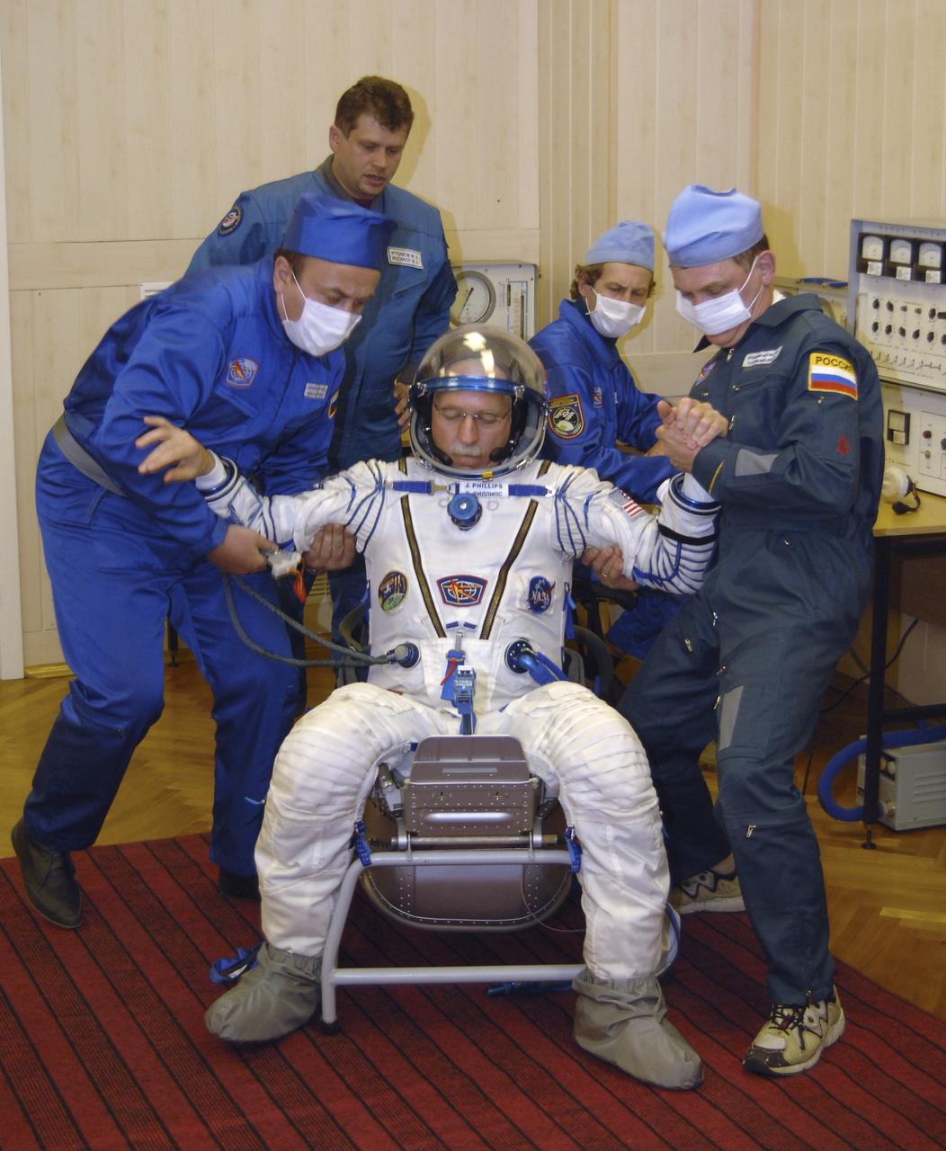 Technicians work on the Russian Sokol suit of Expedition 11 Flight Engineer and NASA Science Officer John Phillips prior to launch aboard the Soyuz TMA-6 spacecraft at the Baikonur Cosmodrome in Baikonur, Kazakhstan, Friday, April 15, 2005 for a two-day trip to the International Space Station. Photo Credit: (NASA/Bill Ingalls)