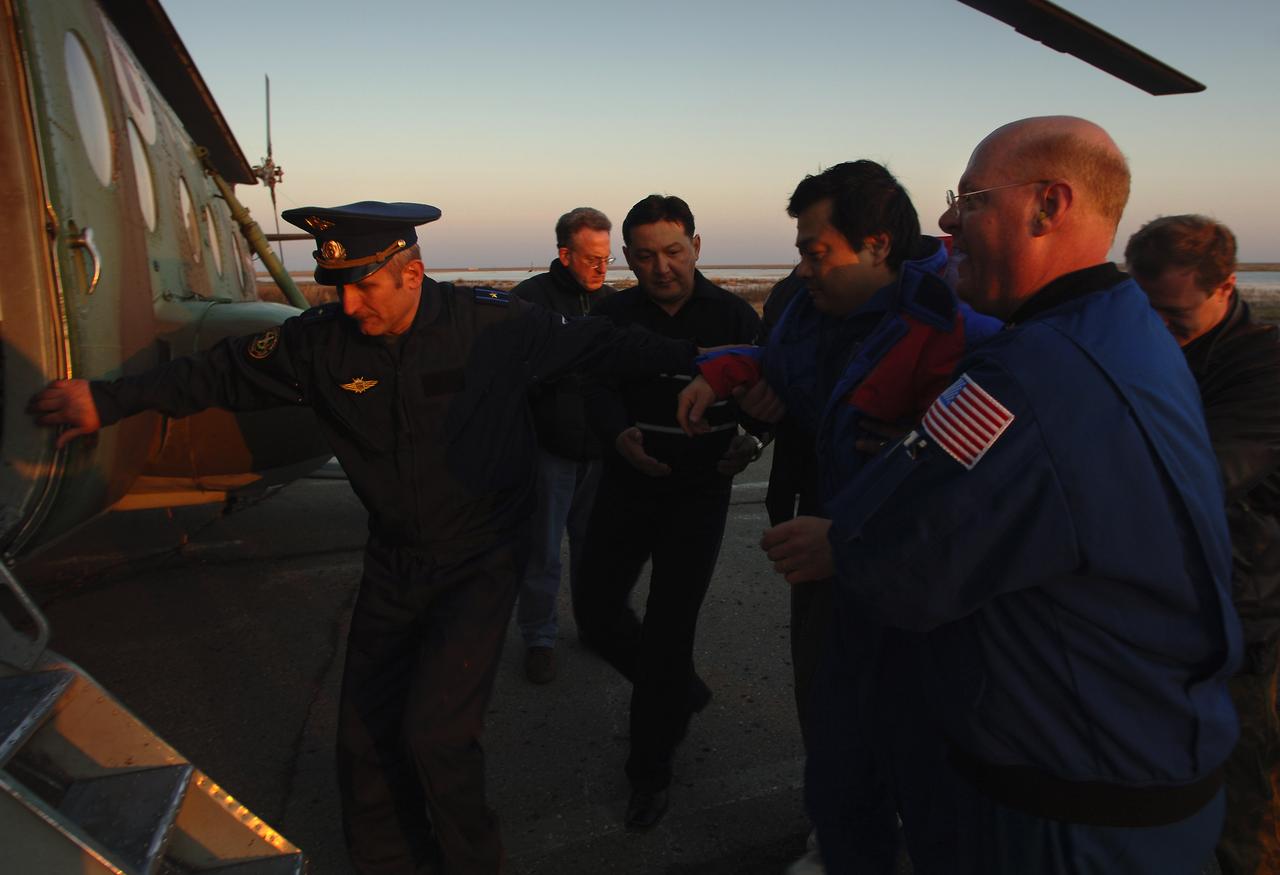 Expedition 10 Commander Leroy Chiao, second from right, is helped onto a Russian search and rescue helicopter after he, Flight Engineer Salizhan Sharipov and European Space Agency astronaut Roberto Vittori brought their Soyuz TMA-5 capsule to a pre-dawn landing, Monday, April 25, 2005, northeast of the town of Arkalyk in Kazakhstan.  Chiao and Sharipov completed a six-month mission aboard the International Space Station, while Vittori, who flew under a commercial contract between ESA and the Russian Federal Space Agency, completed a ten-day mission.  Photo Credit: (NASA/Bill Ingalls)
