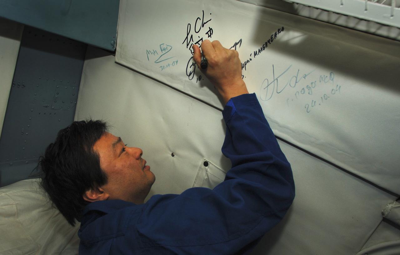 Expedition 10 Commander Leroy Chiao signs the inside of the helicopter that will take him back to Kustanay, Kazakhstan, Monday, April 25, 2005.  Chiao, Flight Engineer Salizhan Sharipov and European Space Agency astronaut Roberto Vittori brought their Soyuz TMA-5 capsule to a pre-dawn landing April 25 northeast of the town of Arkalyk to wrap up a six-month mission aboard the International Space Station for Chiao and Sharipov, and a ten-day mission for Vittori, who flew under a commercial contract between ESA and the Russian Federal Space Agency.  Photo Credit: (NASA/Bill Ingalls)