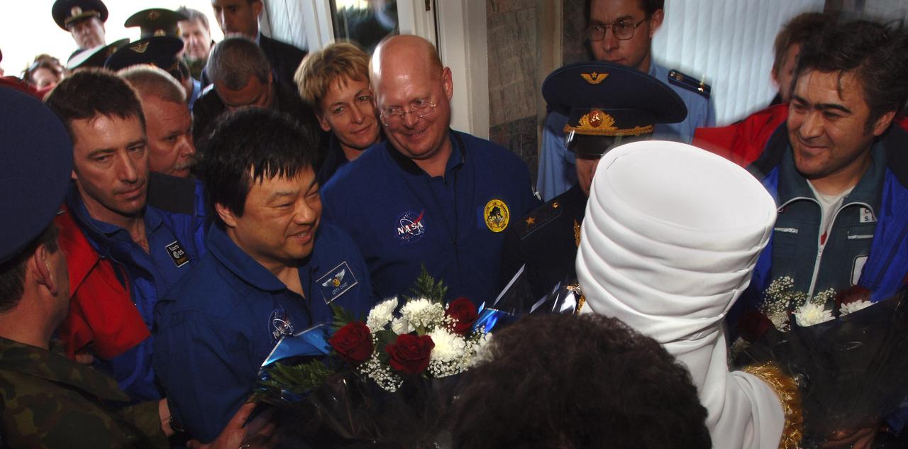 European Space Agency astronaut Roberto Vittori, left, Expedition 10 Commander Leroy Chiao and Flight Engineer Salizhan Sharipov, far right, receive flowers upon arrival in Kustanay, Kazakhstan, Monday, April 25, 2005.  Chiao, Sharipov and Vittori brought their Soyuz TMA-5 capsule to a pre-dawn landing April 25 northeast of the town of Arkalyk to wrap up a six-month mission aboard the International Space Station for Chiao and Sharipov, and a ten-day mission for Vittori, who flew under a commercial contract between ESA and the Russian Federal Space Agency.  Photo Credit: (NASA/Bill Ingalls)