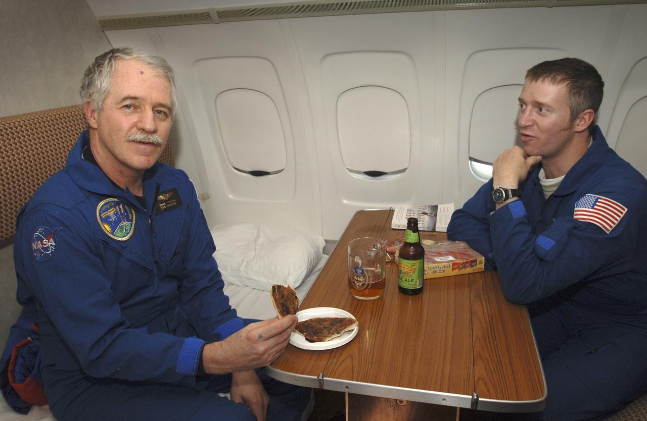 Astronaut John Phillips, left, enjoys a meal onboard a Russian aircraft flying from Kustanay, Kazakhstan to Stary City, Russia, Tuesday, Oct. 11, 2005. Sitting with Philiips is NASA Flight Surgeon Jim Locke. Members of the 11th expedition to the international space station, Phillips and cosmonaut Sergei Krikalev, landed near Arlalyk, Kazakhstan after a six-month mission in orbit. Along with American businessman Greg Olsen, who visited the station for more than a week, Phillips and Krikalev returned to Earth aboard a Russian Soyuz spacecraft. Photo Credit: (NASA/Bill Ingalls)