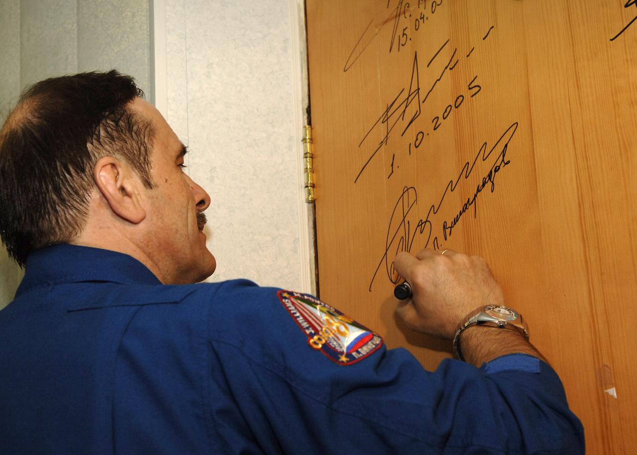 Expedition 13 Commander Pavel V. Vinogradov does the traditional signing of a bedroom door at the Cosmonaut Hotel in Baikonur, Kazakhstan on Thursday, March 30, 2006 prior to the crew’s departure to building 254 and their suit up for launch onboard the Soyuz. Photo Credit: (NASA/Bill Ingalls)