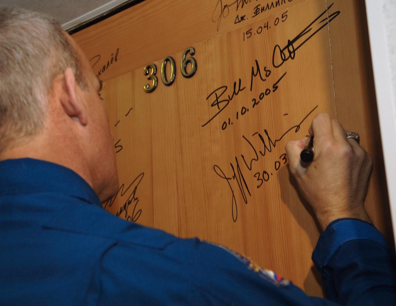 Expedition 13 Science Officer and Flight Engineer Jeffrey N. Williams does the traditional signing of a bedroom door at the Cosmonaut Hotel in Baikonur, Kazakhstan on Thursday, March 30, 2006 prior to the crew’s departure to building 254 and their suit up for launch onboard the Soyuz. Photo Credit: (NASA/Bill Ingalls)