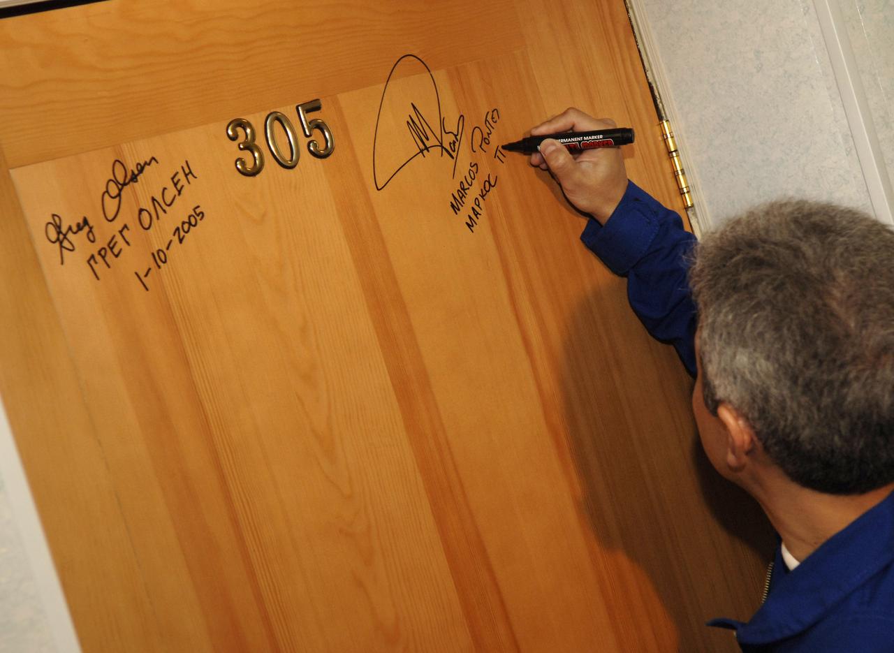 Brazilian Space Agency Soyuz crew member Marcos Pontes performs the traditional signing of a bedroom door at the Cosmonaut Hotel in Baikonur, Kazakhstan on Thursday, March 30, 2006 prior to the crew’s departure to building 254 and their suit up for launch onboard the Soyuz. Photo Credit: (NASA/Bill Ingalls)