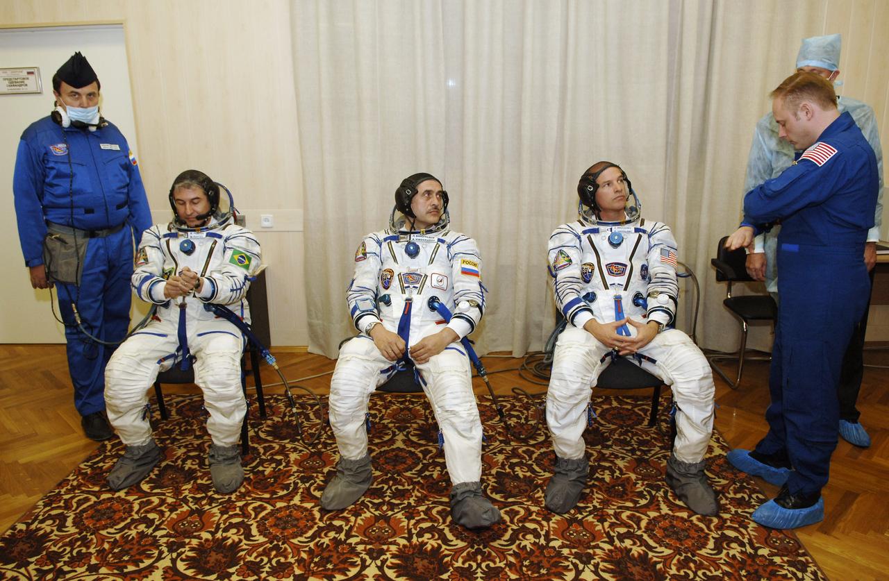 Brazilian Space Agency Soyuz crew member Marcos Pontes, left, and Expedition 13 Commander Pavel V. Vinogradov, and Expedition 13 Science Officer and Flight Engineer Jeffrey N. Williams, right, don their pressure suits in building 254 of the Baikonur Cosmodrome prior to their launch from Baikonur, Kazakhstan. Thursday, March 30, 2006. Photo Credit: (NASA/Bill Ingalls)