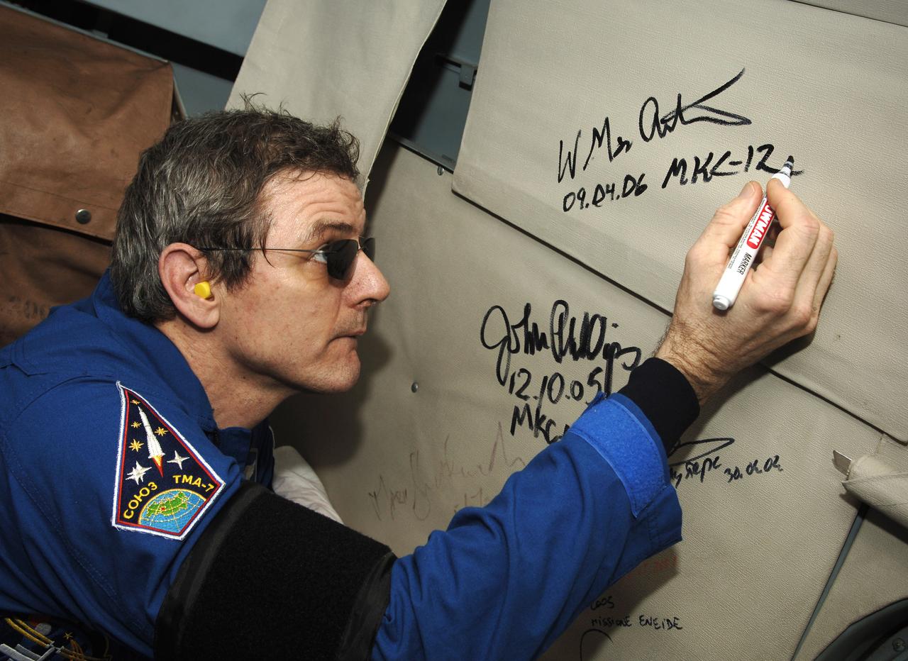 Expedition 12 Commander Bill McArthur signs the interior of the Russian helicopter that will take him from the landing site to Kustanay, Kazakhstan. Expedition 12 returned to Earth and landed in the steppes of Kazakhstan onboard a Soyuz TMA-7 spacecraft that touched down at 7:48 p.m. EDT, Sunday, April 9, 2006. Returning with Commander Bill McArthur and Flight Engineer Valery Tokarev was Brazil’s first astronaut, Marcos Pontes, who arrived at the station with Expedition 13 on April 1. Photo Credit: (NASA/Bill Ingalls)