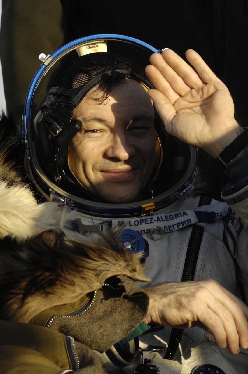 Expedition 14 Commander Michael Lopez-Alegria sits in a chair in front of their Soyuz TMA-9 spacecraft at the landing site as landing and recovery officials conduct post-landing medical checks on the crew. The Soyuz spacecraft landed southwest of Karaganda, Kazakhstan at approximately 6:30pm local time, April 21, 2007. Photo Credit: (NASA/Bill Ingalls)