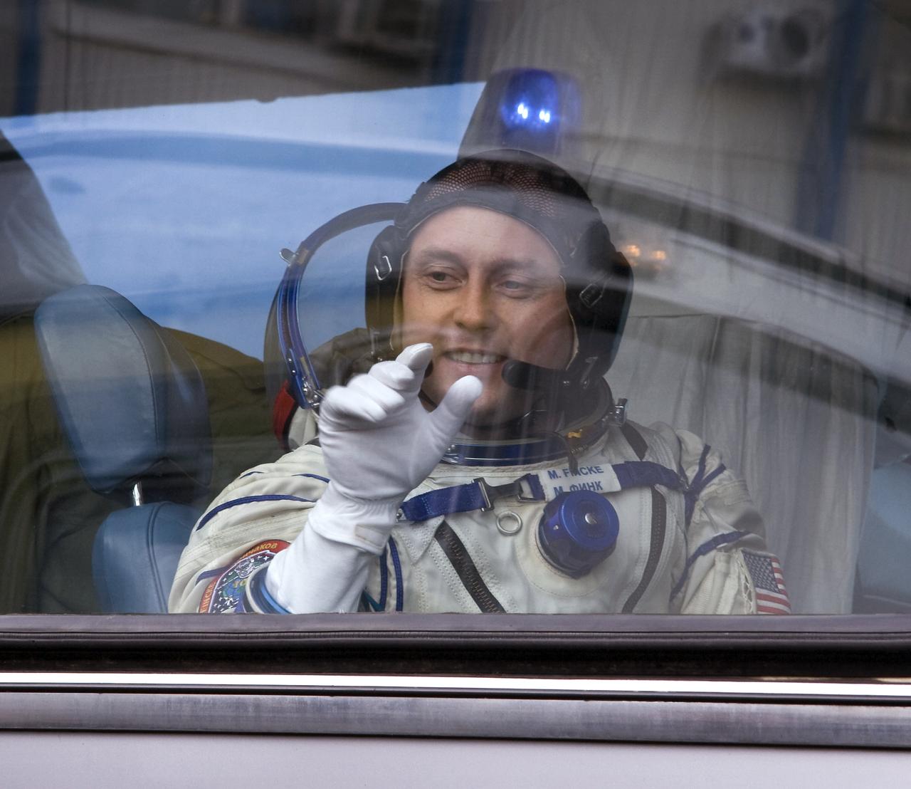 Expedition 18 Commander Michael Fincke waves goodbye to family and friends from the bus that will take him and fellow crew members Flight Engineer Yuri V. Lonchakov and American spaceflight participant Richard Garriott to the Soyuz TMA-13 spacecraft for launch, Sunday, Oct. 12, 2008 from the Baikonur Cosmodrome in Kazakhstan. The three crew members are scheduled to dock with the International Space Station on Oct. 14. Fincke and Lonchakov will spend six months on the station, while Garriott will return to Earth Oct. 24 with two of the Expedition 17 crew members currently on the International Space Station. Photo Credit: (NASA/Victor Zelentsov)