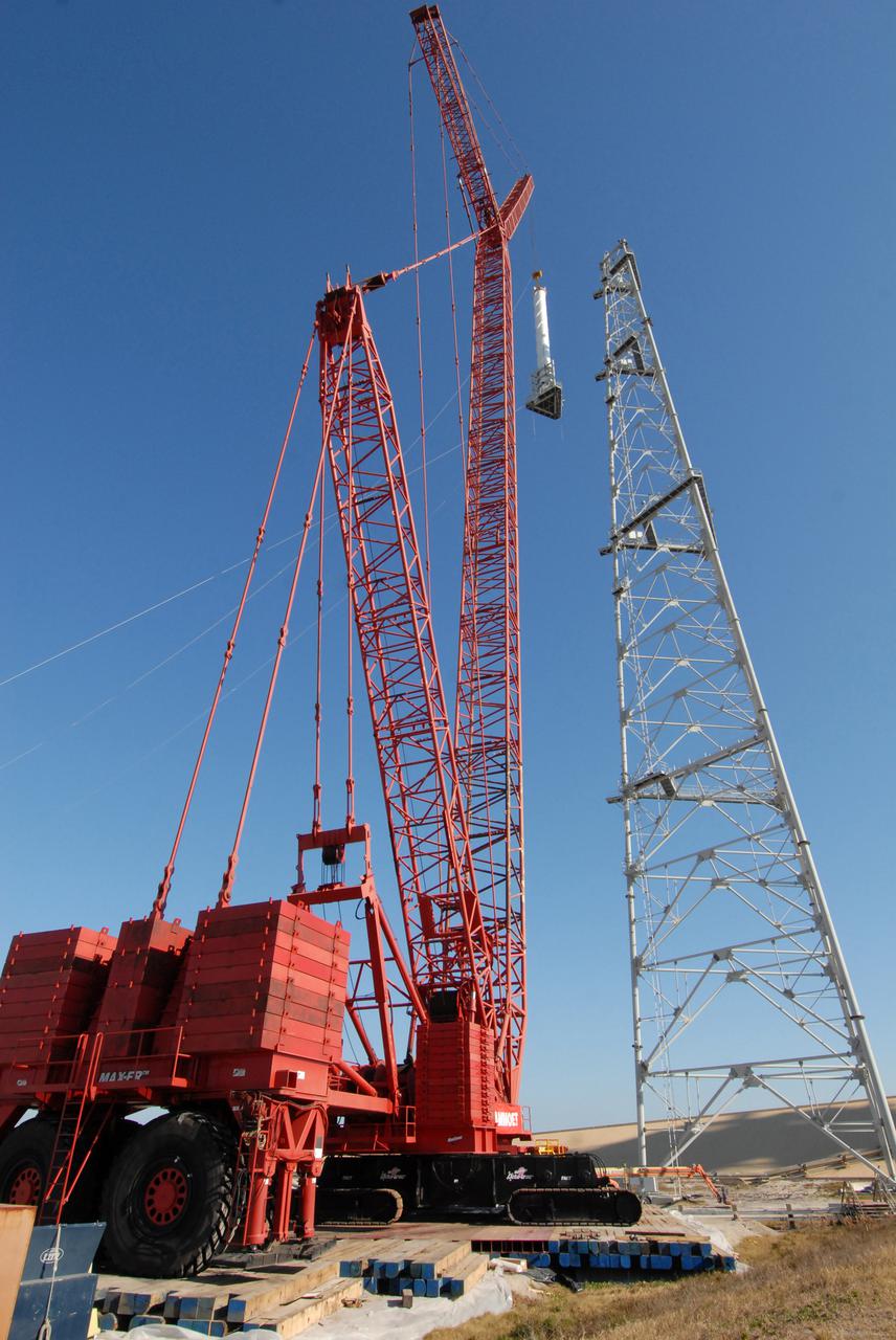 CAPE CANAVERAL, Fla. –  On Launch Pad 39B at NASA's Kennedy Space Center in Florida, a crane lifts a 100-foot fiberglass lightning mast alongside the 500-foot tower where it will be installed.  The tower is one of three being constructed for the Constellation Program and Ares_Orion launches. This improved lightning protection system allows for the taller height of the Ares I rocket compared to the space shuttle.  Pad 39B will be the site of the first Ares vehicle launch, including the Ares I-X test flight that is targeted for July 2009.
