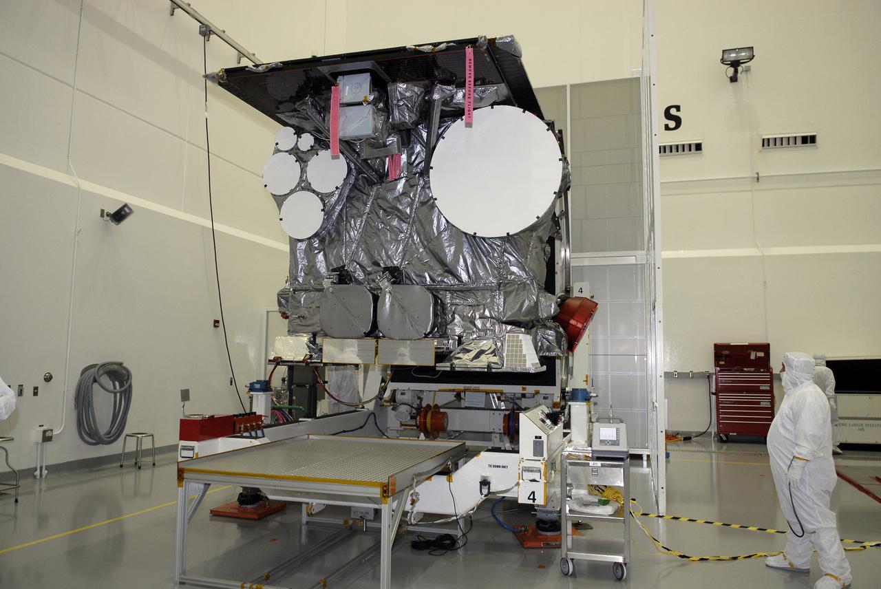 CAPE CANAVERAL, Fla. – At the Astrotech payload processing facility in Titusville, Fla., a technician examines the GOES-O satellite as it completes rotation on the stand. The latest Geostationary Operational Environmental Satellite, GOES-O was developed by NASA for the National Oceanic and Atmospheric Administration, or NOAA. Once in orbit, GOES-O will be designated GOES-14, and NASA will provide on-orbit checkout and then transfer operational responsibility to NOAA. The GOES-O satellite is targeted to launch April 28 onboard a United Launch Alliance Delta IV expendable launch vehicle.  Photo credit: NASA_Kim Shiflett