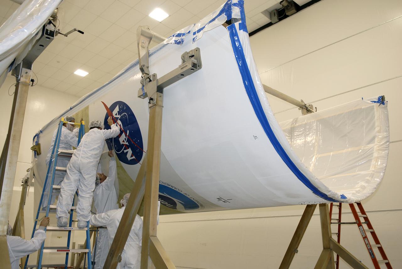 CAPE CANAVERAL, Fla. –  At the Astrotech payload processing facility in Titusville, Fla., technicians apply the NASA logo decal to the fairing that will encapsulate the GOES-O satellite during launch. The latest Geostationary Operational Environmental Satellite, GOES-O was developed by NASA for the National Oceanic and Atmospheric Administration, or NOAA. The GOES satellites continuously provide observations of 60 percent of the Earth including the continental United States, providing weather monitoring and forecast operations as well as a continuous and reliable stream of environmental information and severe weather warnings. Once in orbit, GOES-O will be designated GOES-14, and NASA will provide on-orbit checkout and then transfer operational responsibility to NOAA. The GOES-O satellite is targeted to launch April 28 onboard a United Launch Alliance Delta IV expendable launch vehicle. Photo credit: NASA_Kim Shiflett